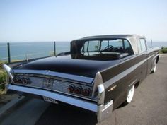 an old car is parked on the side of the road near the ocean and water