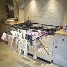 a stove top oven sitting inside of a kitchen next to a counter with clothes hanging on it