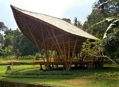 a large wooden structure sitting in the middle of a lush green field next to trees