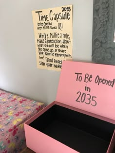 a pink box that says to be opened in 2013 next to a bed with floral bedspread