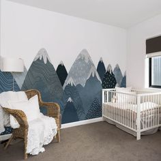 a baby's room with mountains painted on the wall and a crib next to it