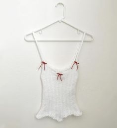 a white bodysuit hanging on a hanger with red string attached to the back