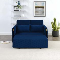 a blue couch sitting on top of a white floor next to a potted plant