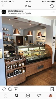 the inside of a coffee shop with lots of food on display and lights hanging from the ceiling