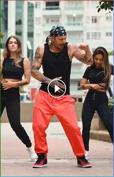 a man in black shirt and red pants doing a dance move with two other women