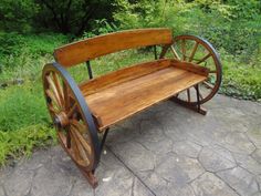 an old wooden bench with wheels on the ground in front of some grass and trees