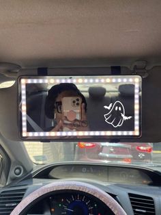 a car dashboard with a lighted mirror on it's side and a person taking a selfie in the front seat