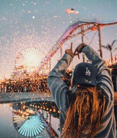 a person standing in front of a ferris wheel with fireworks coming out of the top