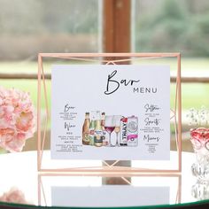 a table with a menu on it and pink flowers in the vase next to it