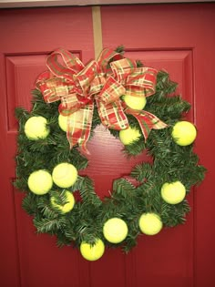 a wreath with tennis balls on it hanging from a red front door decorated for christmas