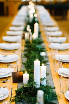 a long table with candles and greenery on it