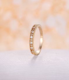 a gold wedding band with small diamonds on it's side, sitting on a white surface