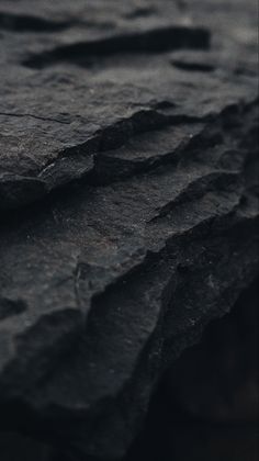 a close up view of some rocks in the water with dark colors and patterns on them