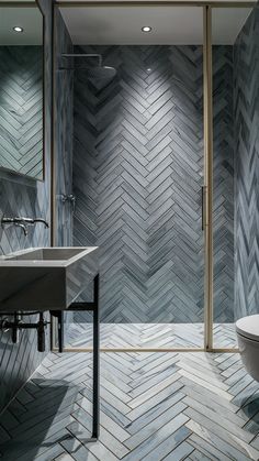 a modern bathroom with herringbone tile on the walls