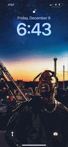 a man with his mouth open standing in front of an amusement park at night time