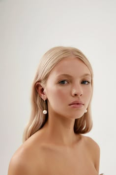 a woman with blonde hair and blue eyes wearing large gold hoop earrings on her ear