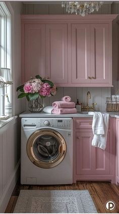 a washer and dryer in a small room with pink cabinets on the walls