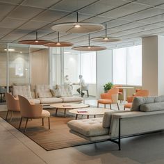 a living room with couches and chairs in it next to a window filled with windows