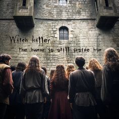 a group of people standing in front of a stone building with writing on the wall