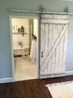 an open barn door in a bathroom with towels hanging on the hooks and towel rack