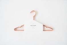 a pink hanger on a white wall with a business card hanging from it's end