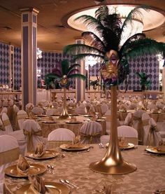 a banquet hall with tables and chairs covered in white tablecloths, gold plates and palm trees