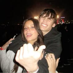 a man and woman standing next to each other in front of a crowd at night