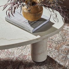 a vase filled with flowers sitting on top of a white table next to a book