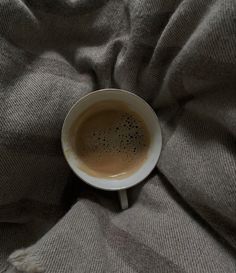 a cup of coffee sitting on top of a bed