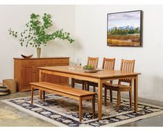 a wooden table with four chairs and a bench in front of a painting on the wall