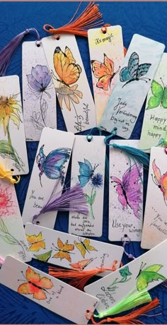 some cards with butterflies on them are sitting on a blue tablecloth and there is an orange string attached to the tags