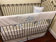 a baby crib with two pillows on top of it and the name j s m in blue