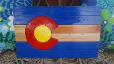 a wooden sign with the flag of colorado painted on it