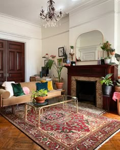 a living room filled with furniture and a fire place under a chandelier on top of a wooden floor