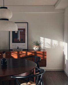 a dining room table with four chairs and a plant in the corner next to it