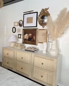 a white dresser topped with lots of pictures and vases