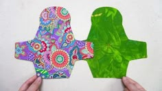 two people made out of paper with green and pink designs on them, one is holding the other