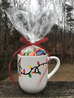 a coffee cup filled with candy and wrapped in cellophane on top of a wooden table