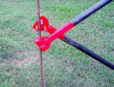 a red fire hydrant sitting on top of a lush green field next to a metal pole