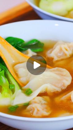 a bowl filled with dumplings and broccoli on top of a wooden table