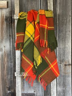 an orange and green plaid blanket hanging on a wooden door