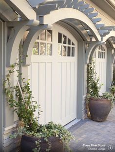 two large planters sitting next to each other on a brick walkway in front of a house