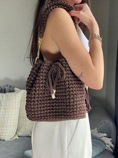 a woman holding onto a brown knitted bag