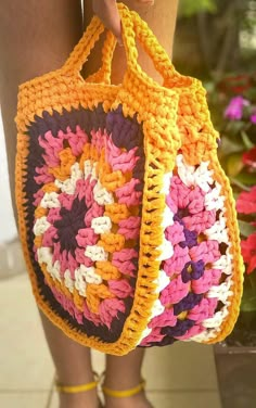 a woman is holding a crocheted bag in her hand