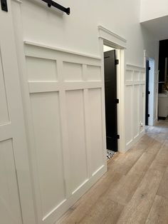 an empty room with wooden floors and white walls, along with black door handles on the doors