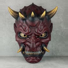 a red demon mask with gold horns on it's head