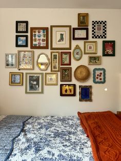 a bedroom with many framed pictures on the wall