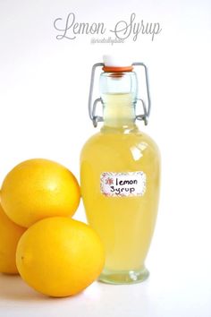 lemon syrup in a glass bottle next to three lemons on a white background with the words lemon syrup above it