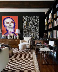 a living room filled with furniture and bookshelves next to a painting on the wall