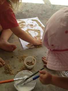 two children are making sand art on the ground